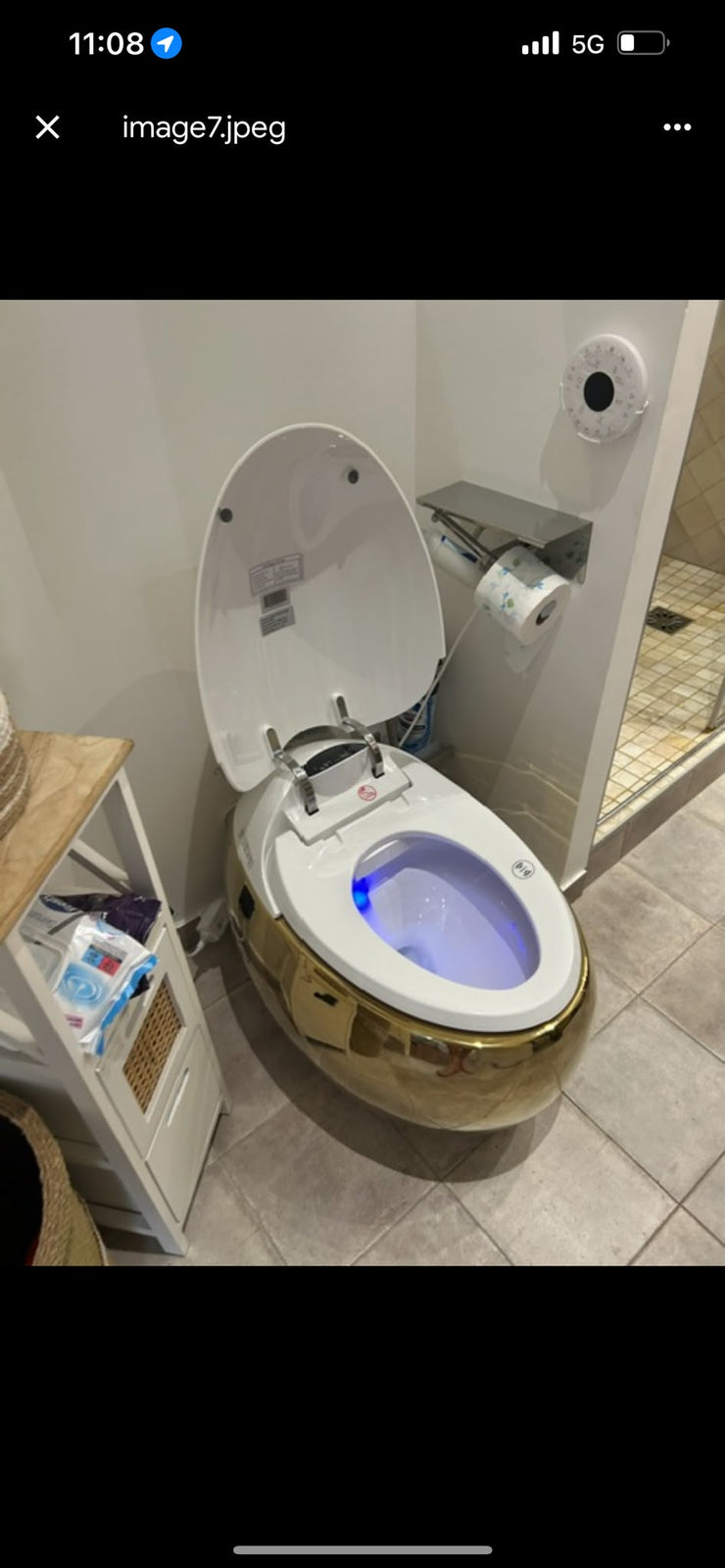 WC japonais doré avec abattant ouvert et éclairage bleu installé chez un client près d’une douche.