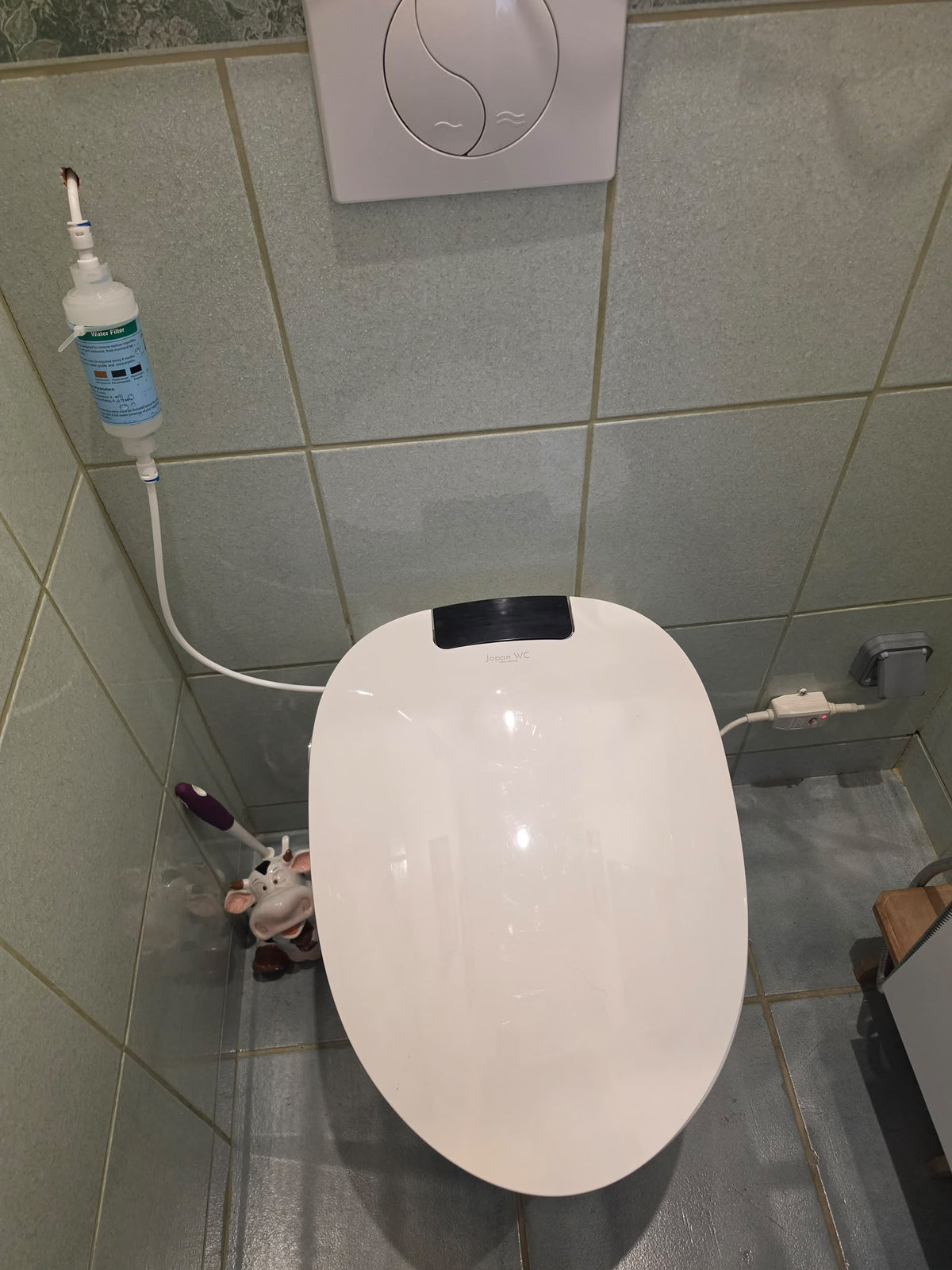WC japonais suspendu blanc installé chez un client dans une pièce aux murs carrelés.