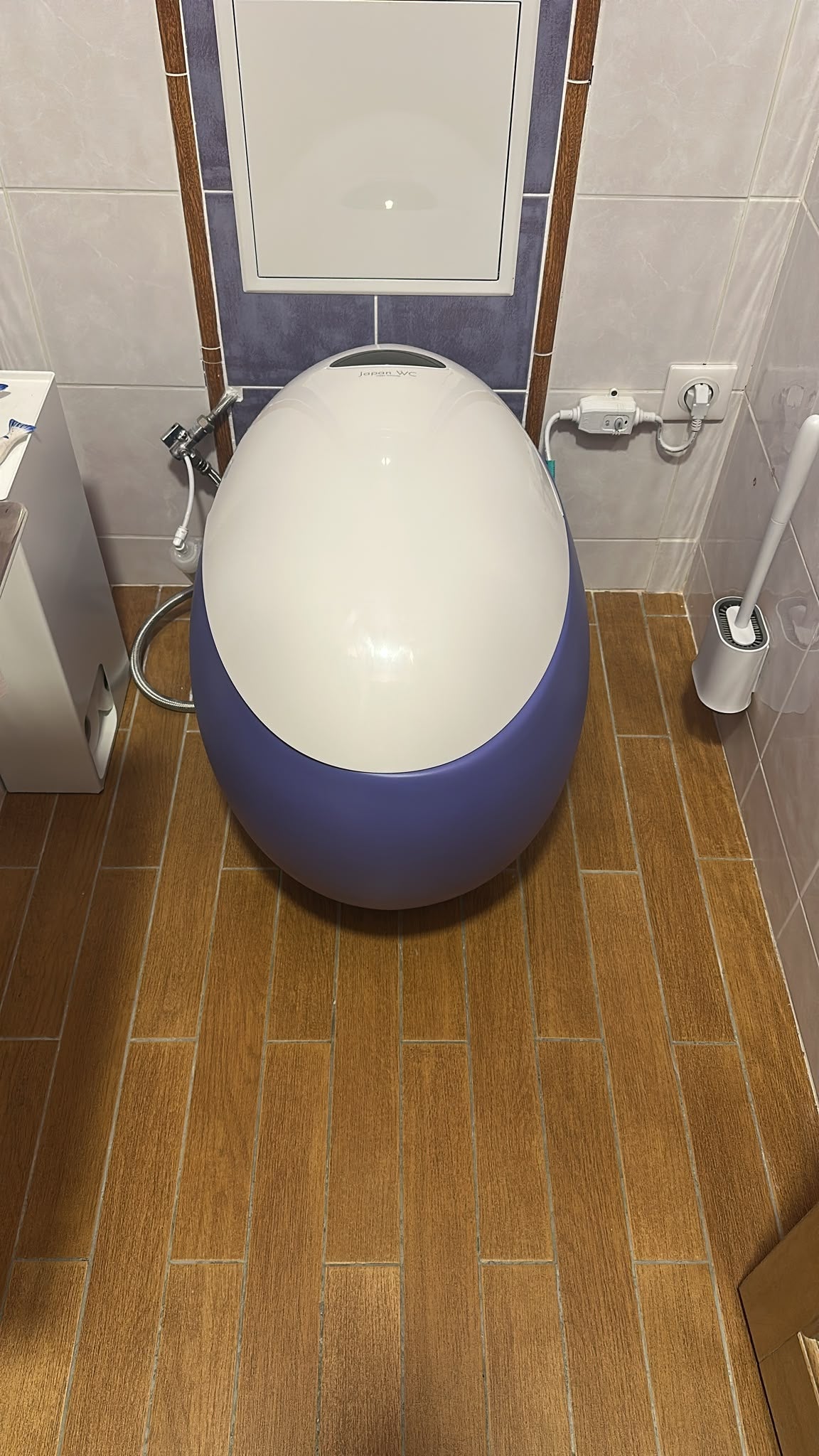 WC japonais violet avec abattant blanc installé chez un client, sur un sol imitation bois.